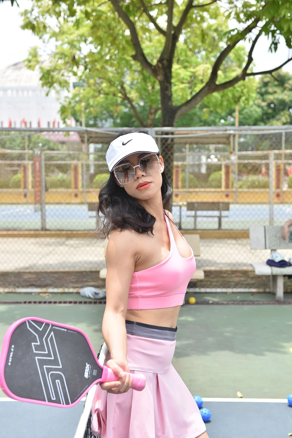 ピンクのトップスとスカート、白いバイザーを身につけてパドルを持つ女性